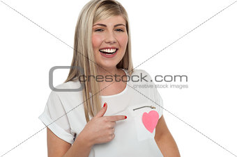 Pretty teen pointing towards pink paper heart