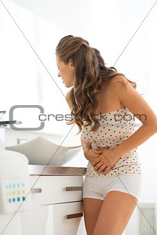 Young woman with abdominal pain in bathroom
