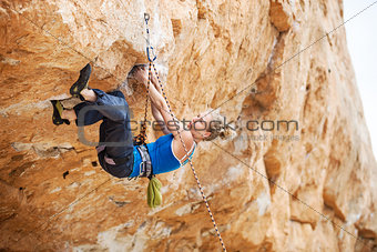 Young female rock climber struggling to make next movement up