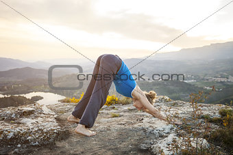 Young Caucasian woman performing downward dog yoga pose outdoors