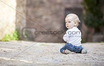 Little boy crawling on stone paved sidewalk
