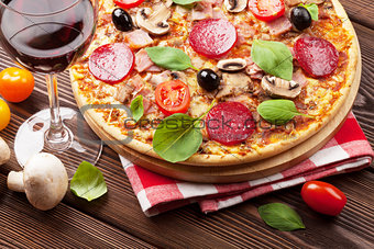 Italian pizza with pepperoni, tomatoes, olives, basil and red wi