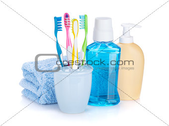 Four colorful toothbrushes, cosmetics bottles and towel