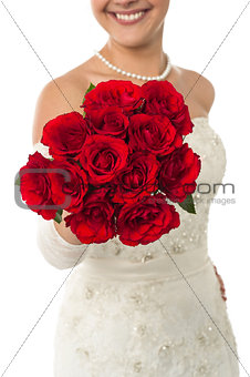 Smiling young bride holding out a rose bouquet