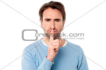 Young male holds finger on his lips