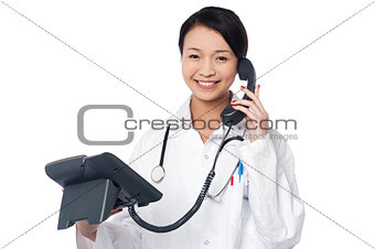 Young lady doctor answering phone call