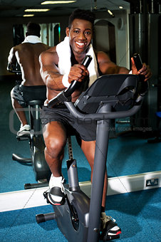 Muscular man on excercise bike at the gym