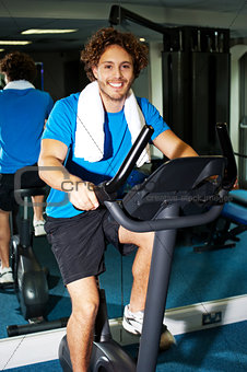 Fitness man riding a static bike inside gym