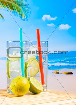 glasses of cocktail with lime slice on blur beach