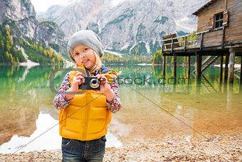 Young blonde girl on shores of Lake Bries holding a camera