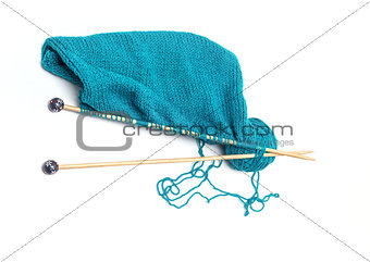 blue yarn with knitted fabric and knitting needles