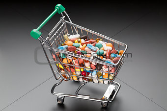 Shop cart with different colorful pills on black