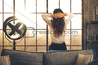 Woman standing in a loft with hands laced behind her head