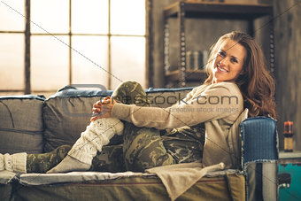 Casually dressed woman sitting on sofa smiling
