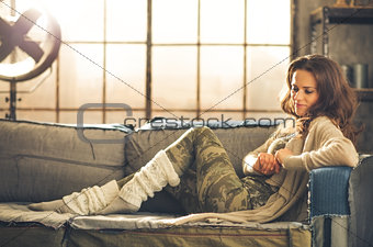 Woman sitting on sofa in loft relaxing