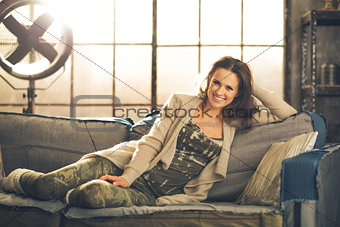 Woman front-facing sitting on sofa in loft relaxing smiling