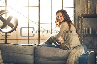 Smiling woman looking over shoulder sitting on sofa back