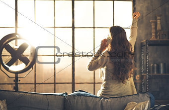 Woman seen from behind talking on phone in front of loft window