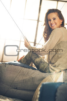 Woman in loft smiling and looking over shoulder holding phone