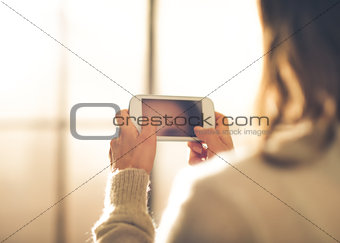 Closeup of woman seen from behind holding mobile phone