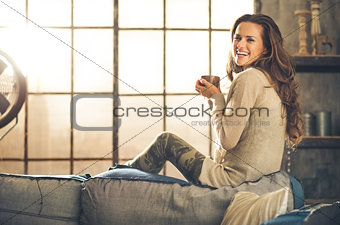 Profile shot, woman smiling looking over shoulder holding cup