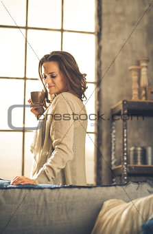 Brunette holding cup of coffee in loft