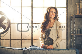 Casual brunette with coffee smiling in loft apartment