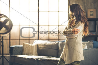 Brunette looking away holding phone in a loft apartment