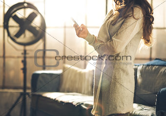 Close-up of brunette holding phone in loft, torso shot