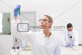 Scientist examining green precipitate in tube
