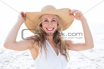 Smiling blonde in white dress looking at camera and wearing straw hat