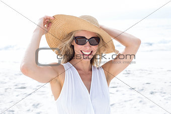 Smiling blonde in white dress wearing sun glasses and straw hat