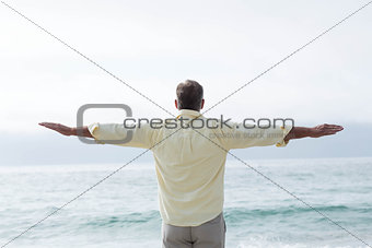 Thoughtful man standing by the sea arms outstretched