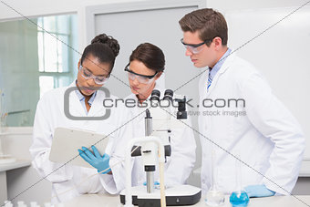 Scientists working with microscope and taking notes
