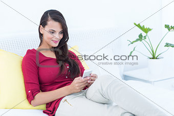 Beautiful woman using her smartphone sitting on bed