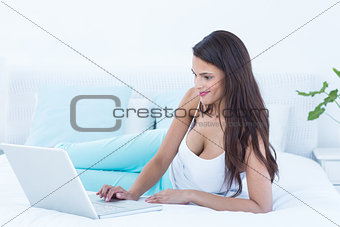 Beautiful woman using laptop on her bed