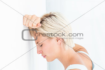 Sad blonde woman with her head on wall