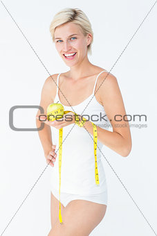 Happy woman holding an apple with hand on hip