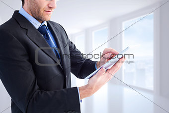 Composite image of mid section of a businessman using digital tablet
