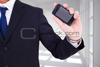 Composite image of mid section of a businessman typing on his phone