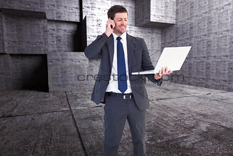Composite image of businessman talking on phone holding laptop