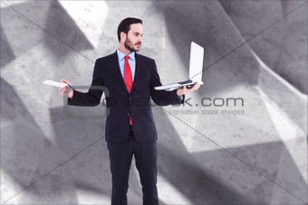Composite image of handsome businessman holding his laptop