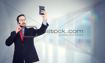 Composite image of businessman holding calculator while talking on phone
