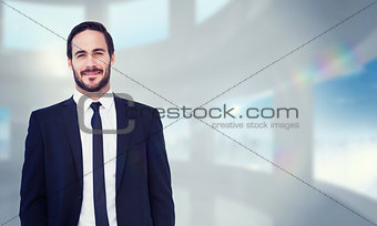 Composite image of smiling businessman in suit standing with hands in pockets