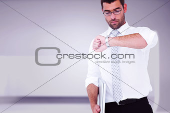 Composite image of serious businessman holding laptop checking time