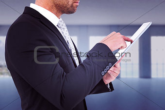Composite image of businessman using his tablet pc