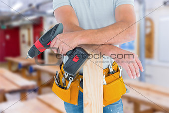 Composite image of midsection of male carpenter with power drill and plank