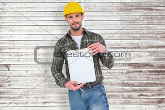 Composite image of smiling manual worker holding clipboard