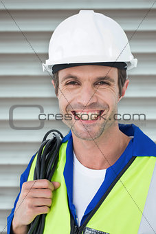 Composite image of happy electrician with wire against white background