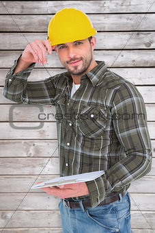 Composite image of smiling handyman writing on clipboard